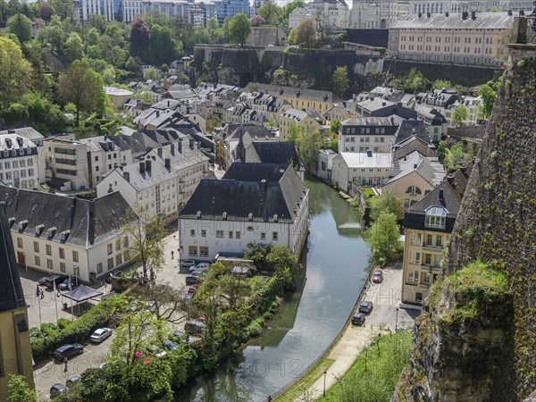 View of an old town with historic buildings by a river and green surroundings, Luxembourg City,