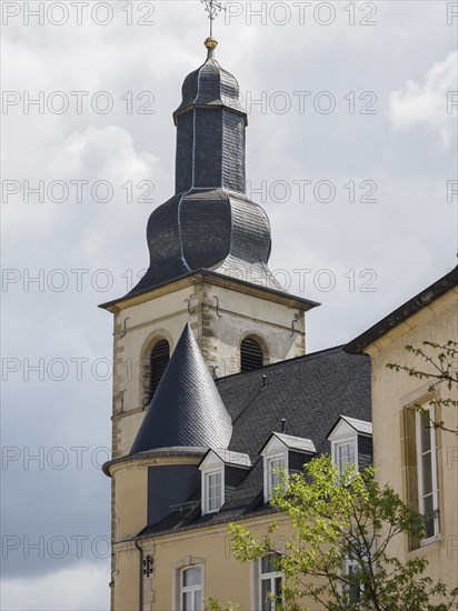 A church tower and a historic building under a bright, cloudy sky, Luxembourg City, Luxembourg,