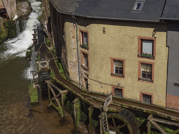 Watermill with old buildings on the river, detail of the wooden structure and wheels, Saarburg,