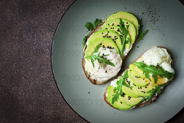 Sandwich with cream cheese, sliced avocado and boiled egg, arugula, on grainy bread, homemade,