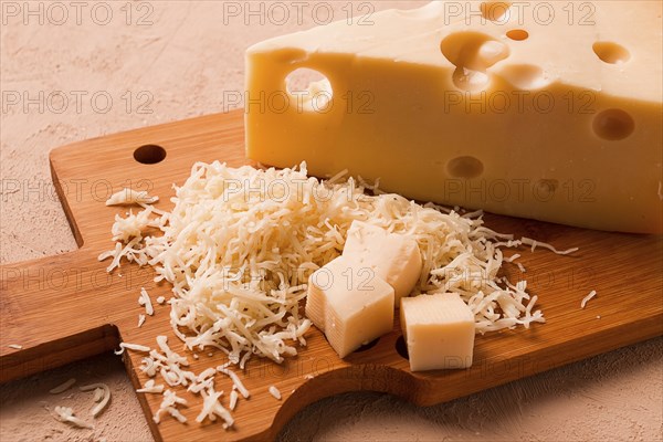 Geriebener Käse, Maasdam, auf einem Schneidebrett, Reibe und Käsemesser, Nahaufnahme, keine