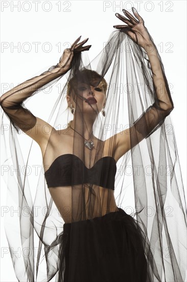 Beautiful woman in a transparent black skirt, bodice and neck decoration posing on a white