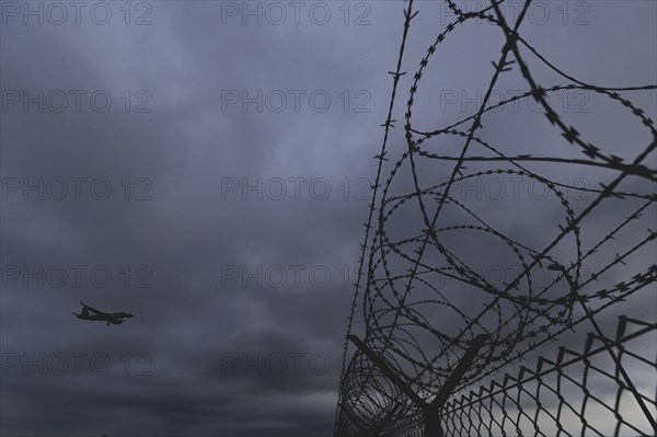 An aircraft looms over a barbed wire fence, taken at Berlin Brandenburg Airport 'Willy Brandt'Äô