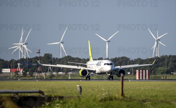 Air Baltic aircraft landing at Amsterdam Schiphol Airport, Polderbaan, 18R/36L, wind farm in the