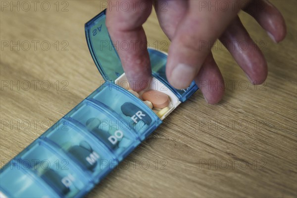 An elderly man takes pills from a pill box. Berlin, 05.08.2024