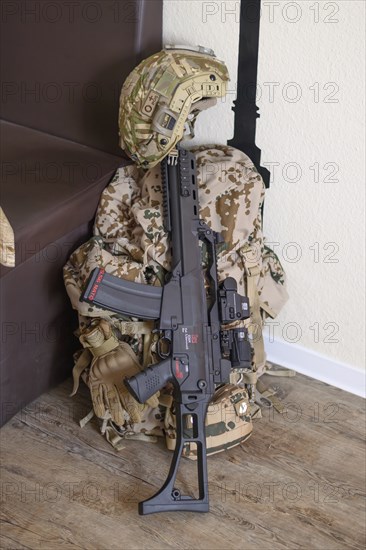 A military helmet and a rifle lie on a camouflaged rucksack on a wooden floor, mobilisation,