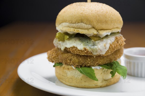 Close-up of homemade tasty chicken burger on wooden table and black background