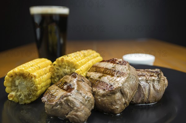 Delicious filet mignon close-up with roasted corn and glass of beer