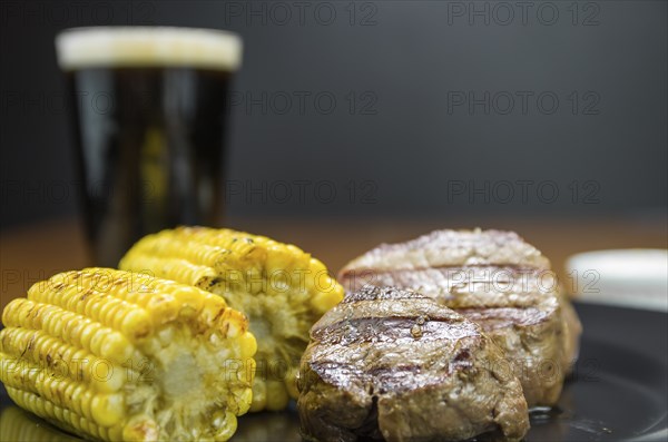 Delicious filet mignon close-up with roasted corn and glass of beer