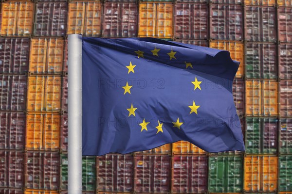 Symbolic image of the economy in the EU: EU flag in front of a large stack of shipping containers