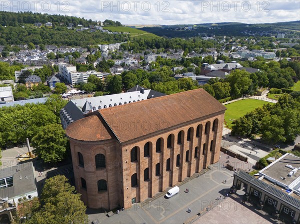 Ancient Roman building made of brick, seen from above, surrounded by city elements and green trees