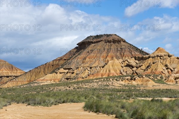 Rocky hill in an arid landscape under a blue sky with clouds, Bardenas Reales Natural Park, desert,