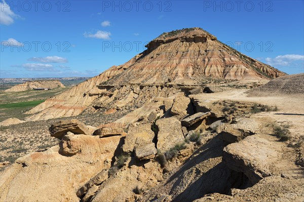 Stony hill in a desert-like landscape under a blue sky with few clouds, Bardenas Reales Natural