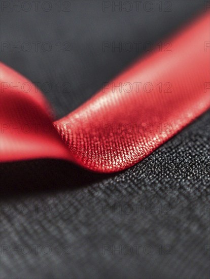 Close-up of a red satin ribbon placed on a black textured background, AI generated
