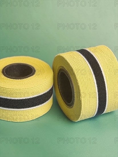 Two rolls of yellow ribbon with a black stripe on a green background, AI generated