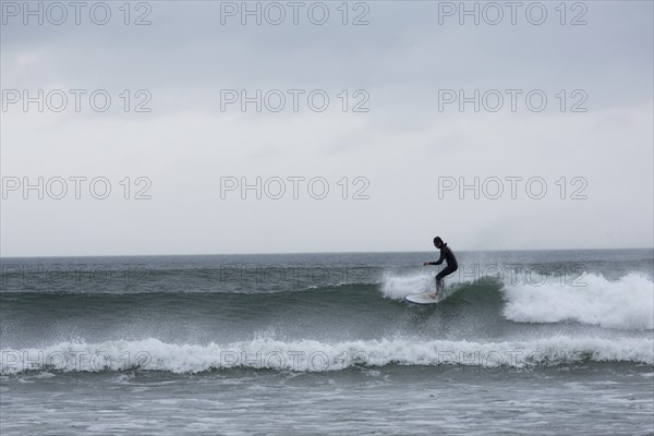 A surfer enjoys the high waves at Strandhill along Wild Atlantic way on the west coast of Ireland.,