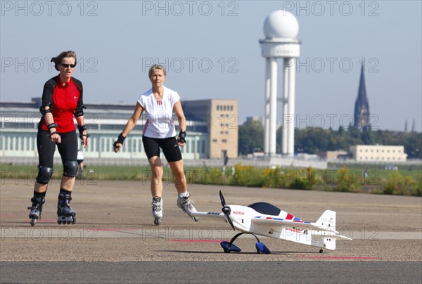Berlin, 12.10.09 2010, Rollerbladers drive past a model aeroplane on the runway of the former
