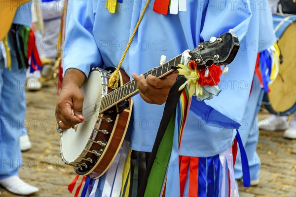 Banjoist on the streets of Brazil wearing colorful clothes during a traditional religious festival,