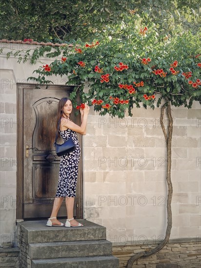 Young woman enjoys a beautiful summer day in vacation standing at the threshold of a door smelling