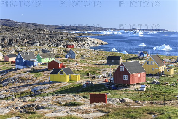 Typical Greenlandic houses, Inuit settlement in front of icebergs, Qeqertaq, Disko Bay, West