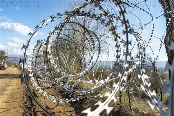 Spiral barbed wire installation beside a road in daylight, highlighting security and open