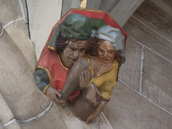 Man with beer glass and woman with money, console figures in Heilig Kreuz Minster, Rottweil,