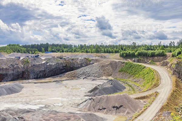 Road to a industrial open pit with gravel piles in the forest