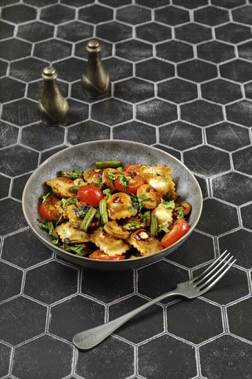 Fried ravioli with chicken meat served with seared green beans, tomato and mushrooms