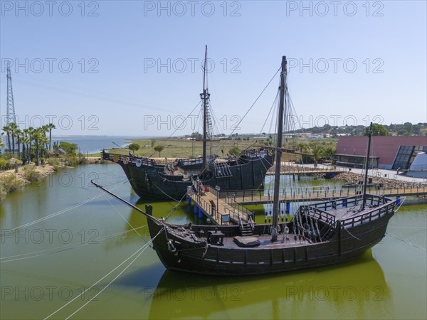 Resting harbour with historical replicas of sailing ships in the water under a clear sky, aerial