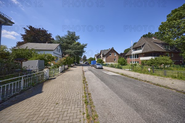 Road through a residential area with detached houses and apartment blocks in the district of