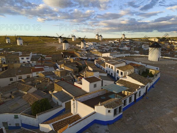Aerial view of a Spanish village with traditional white houses and windmills under a blue sky with
