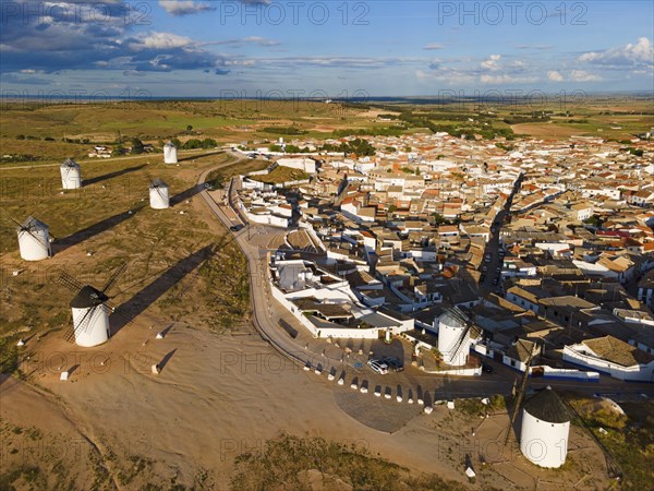 Aerial view of windmills near a village in sunny weather with blue sky and clouds. The white