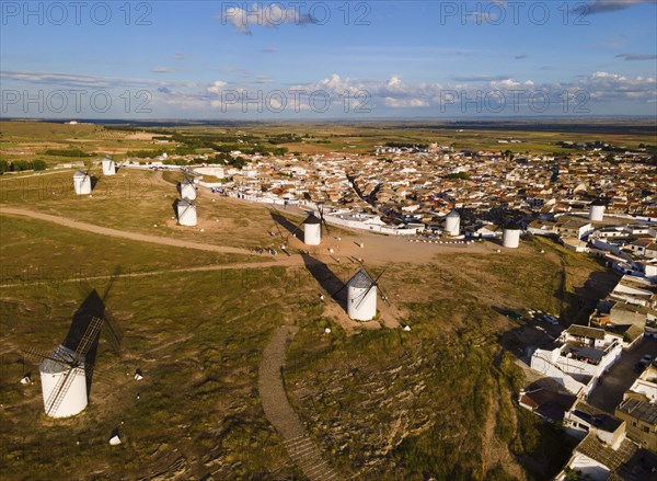 Windmills scattered on a hill near a village in sunny weather with blue skies and clouds. The