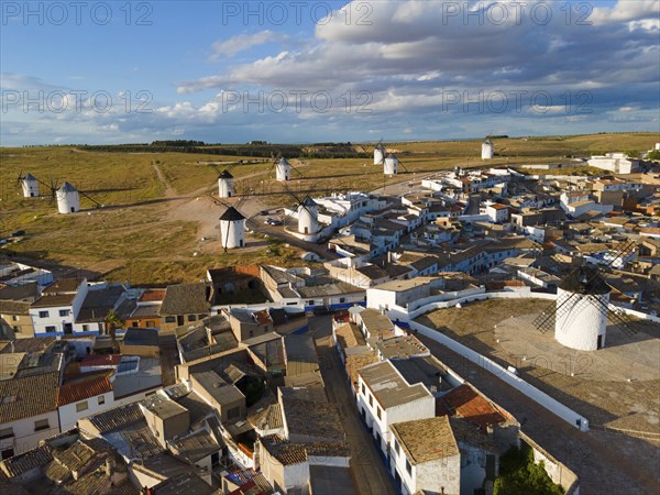 View of a village with windmills in the background in sunny weather and partly cloudy skies. Many