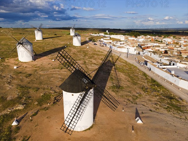 Windmills in a rural setting in sunny weather with blue sky and clouds. In the background a village