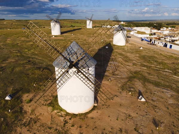 Close-up of several windmills in a green landscape under a blue sky with clouds, aerial view,