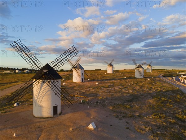 Several windmills are scattered in a wide landscape under a slightly cloudy sky, aerial view,