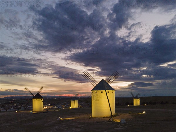 Several illuminated windmills in a rural landscape at sunset, aerial view, windmills, Campo de