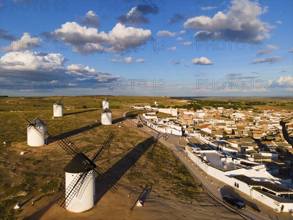 Aerial view of windmills and a village under a blue sky with clouds and long shadows, aerial view,