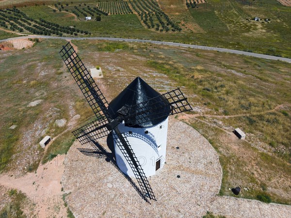 Aerial view of a white windmill in a green, rural landscape under a sunny sky, aerial view, Alcazar