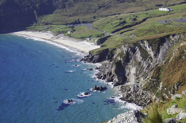 View of rocky coastline with beach and houses in the background, Kell Beach, Achill Island, County
