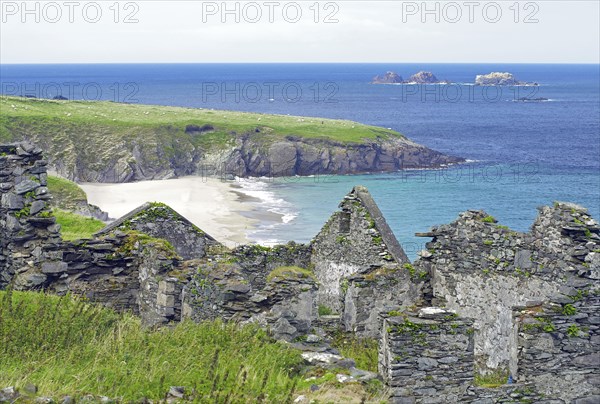 Ruins on a rocky coast with green grass and blue sea, Blasket Islands, Dunmore Head, Ireland,