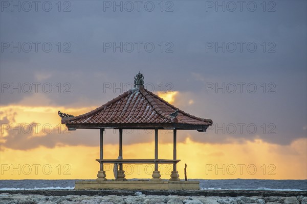 Fantastic sunrise on the beach with small temples and built as breakwaters. View of the sea as far