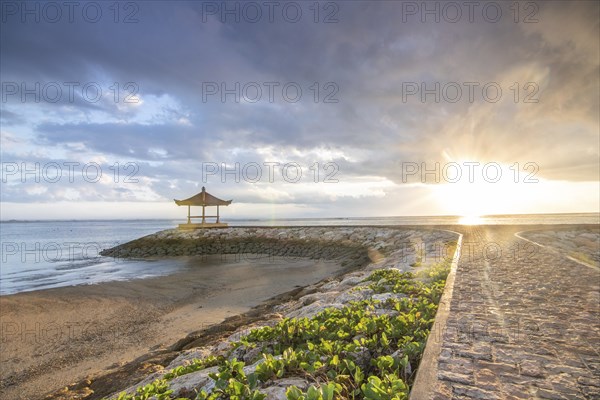 Fantastic sunrise on the beach with small temples and built as breakwaters. View of the sea as far