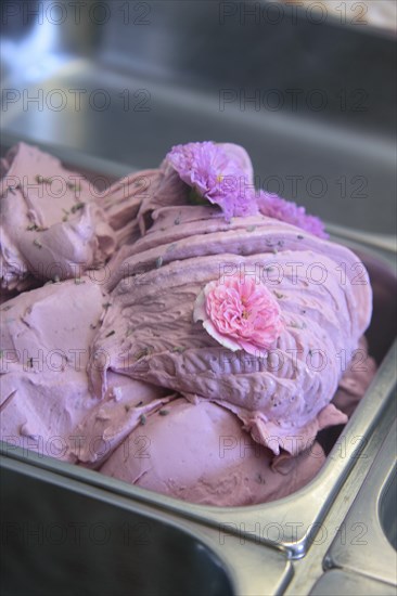 Close-up of pink ice cream with flowers in a stainless steel tray