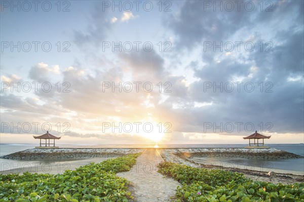Fantastic sunrise on the beach with small temples and built as breakwaters. View of the sea as far