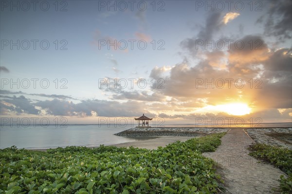 Fantastic sunrise on the beach with small temples and built as breakwaters. View of the sea as far