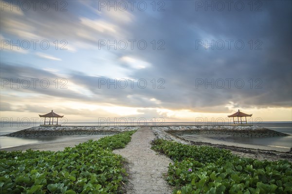 Fantastic sunrise on the beach with small temples and built as breakwaters. View of the sea as far