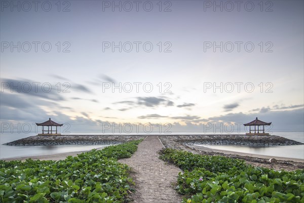 Fantastic sunrise on the beach with small temples and built as breakwaters. View of the sea as far