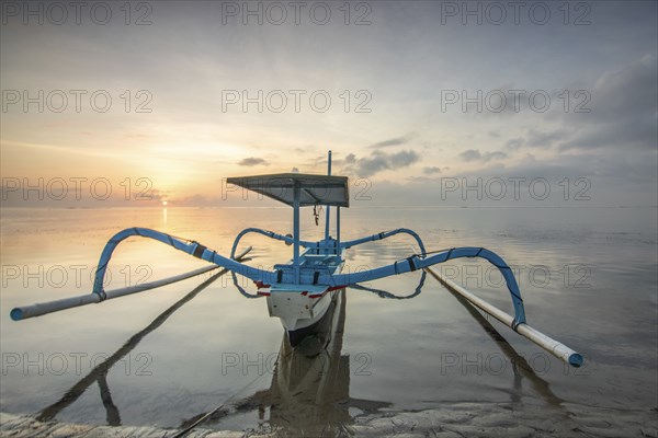 Fantastic sunrise on the beach with small temples and a traditional fishing boat, Jukung. View of
